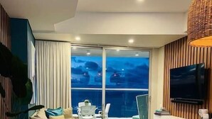 A modern living room with a sofa, a coffee table, and a TV. There is a balcony with a view of the city. - SPECTACULAR Jewel @ Palmetto Eliptic Bocagrande 34th Floor (Cartagena de Indias)