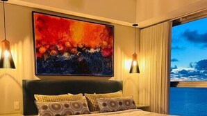 A modern bedroom with a large bed, a painting above the bed, and a view of the sea through a large window. - SPECTACULAR Jewel @ Palmetto Eliptic Bocagrande 34th Floor (Cartagena de Indias)