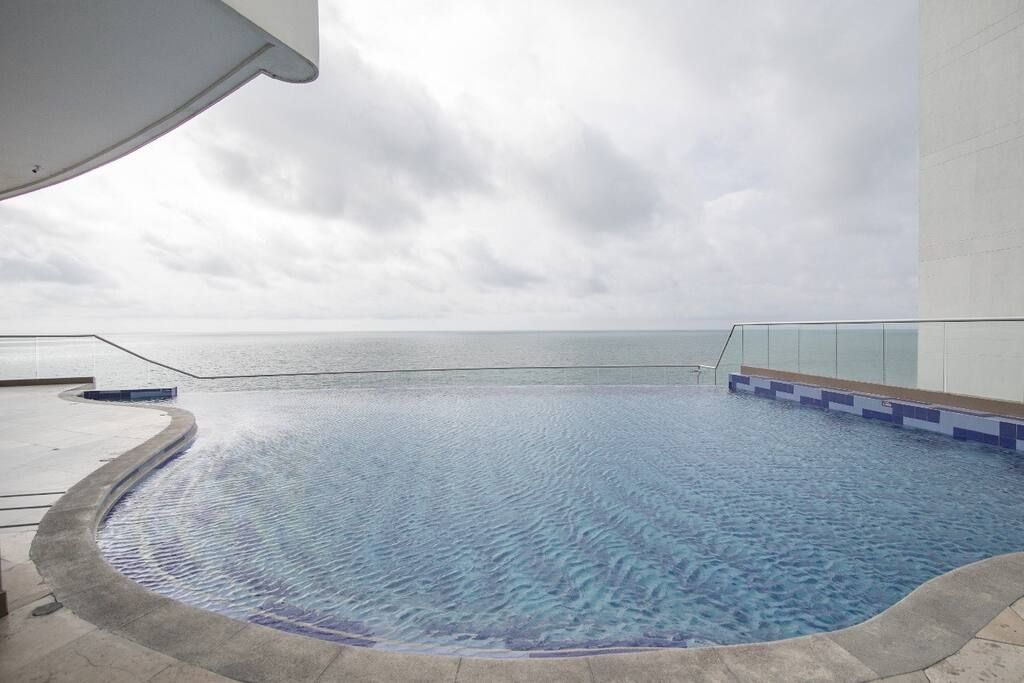 A swimming pool with a view of the sea, surrounded by a modern building.