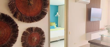 A modern room with a bed, a TV, and a bathroom with a mirror and sink.