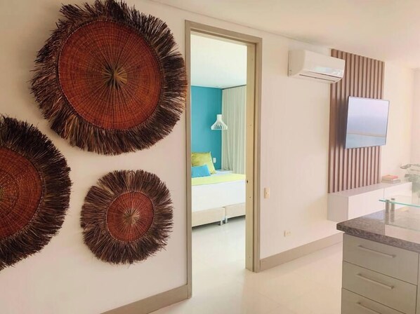 A modern room with a bed, a TV, and a bathroom with a mirror and sink.