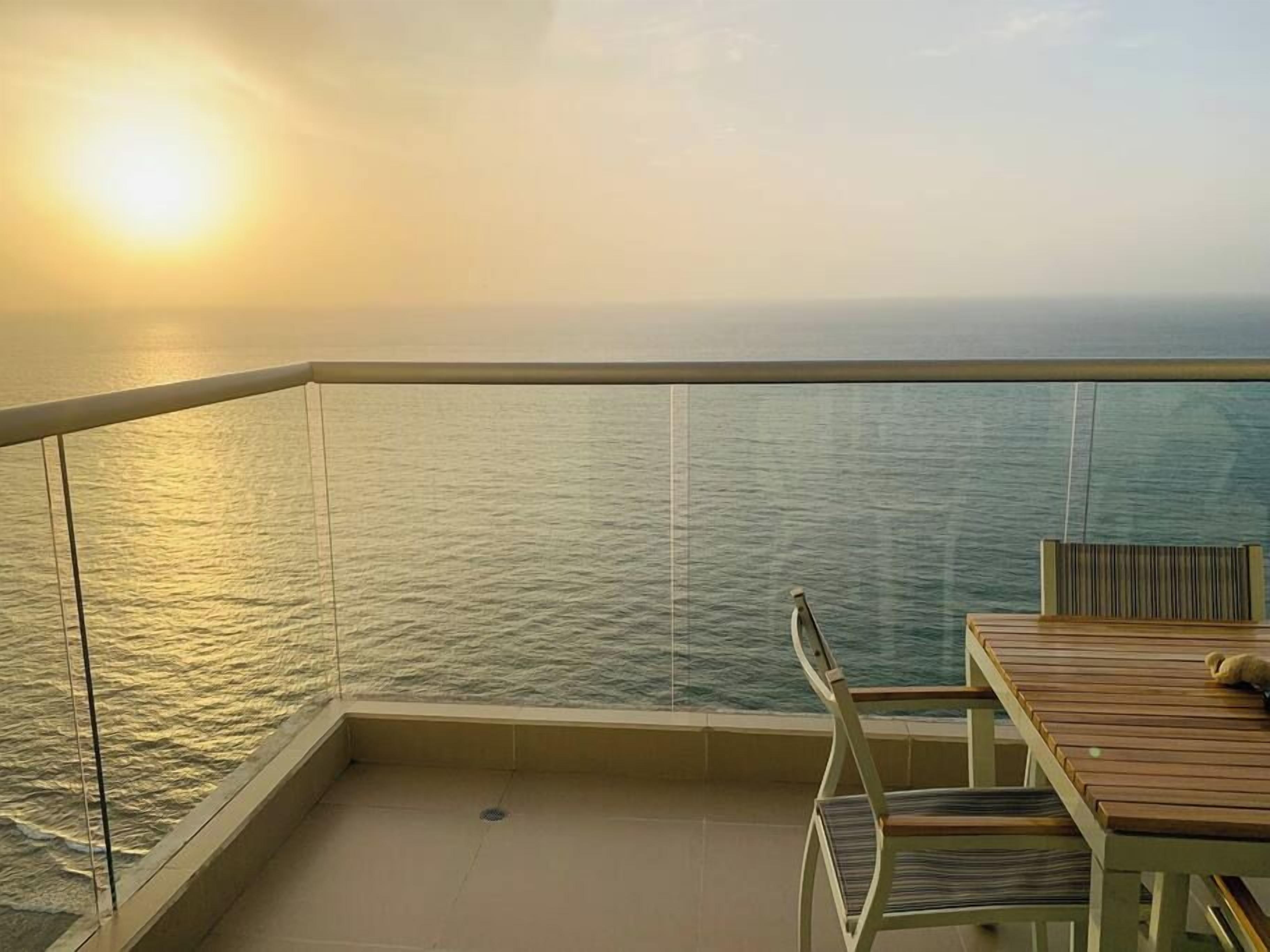 A balcony with a view of the sea during sunset.