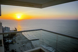A balcony with a view of the sea at sunset.