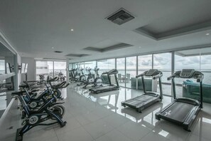 A gym with stationary bikes, treadmills, and a large window overlooking the sea. - SPECTACULAR Jewel @ Palmetto Beach Bocagrande 32th Floor (Cartagena de Indias)