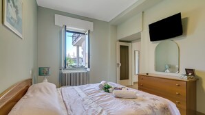 A bedroom with a bed, a dresser, a mirror, and a window. - Il Giardino Di Dante Stresa Center: 2BR Terrace Apartment (Stresa)