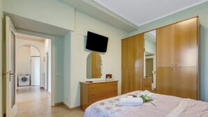 A bedroom with a bed, a dresser, a television, and a wardrobe. - Il Giardino Di Dante Stresa Center: 2BR Terrace Apartment (Stresa)