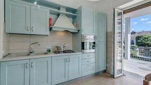 A modern kitchen with light blue cabinets, a gas stove, an oven, and a sink. - Il Giardino Di Dante Stresa Center: 2BR Terrace Apartment (Stresa)