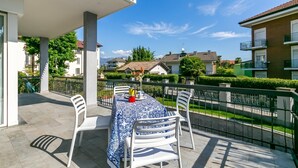 A balcony with a table set for two, white chairs, and a blue tablecloth. - Il Giardino Di Dante Stresa Center: 2BR Terrace Apartment (Stresa)