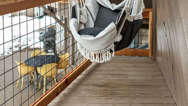 Ett trädäck med en vit hängstol.