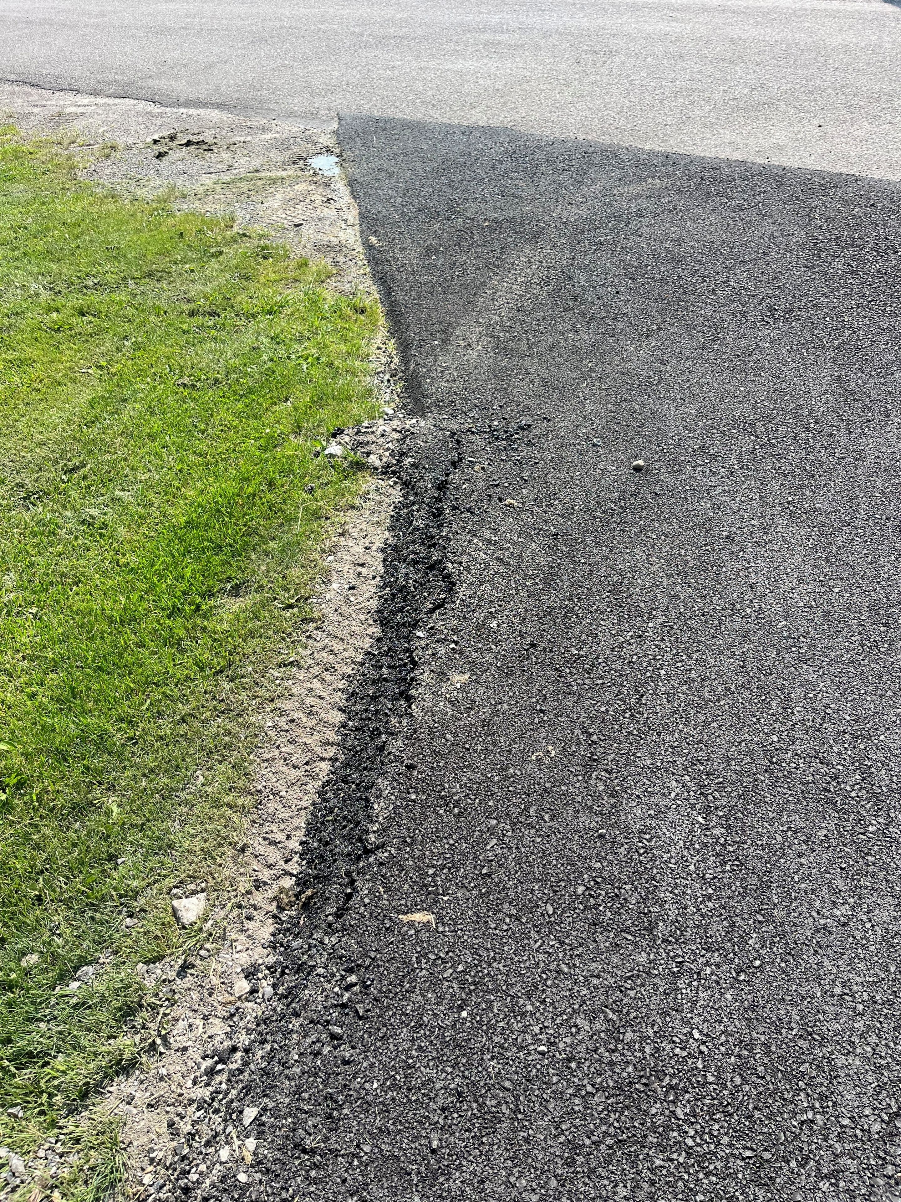 A road with a visible crack and uneven surface.