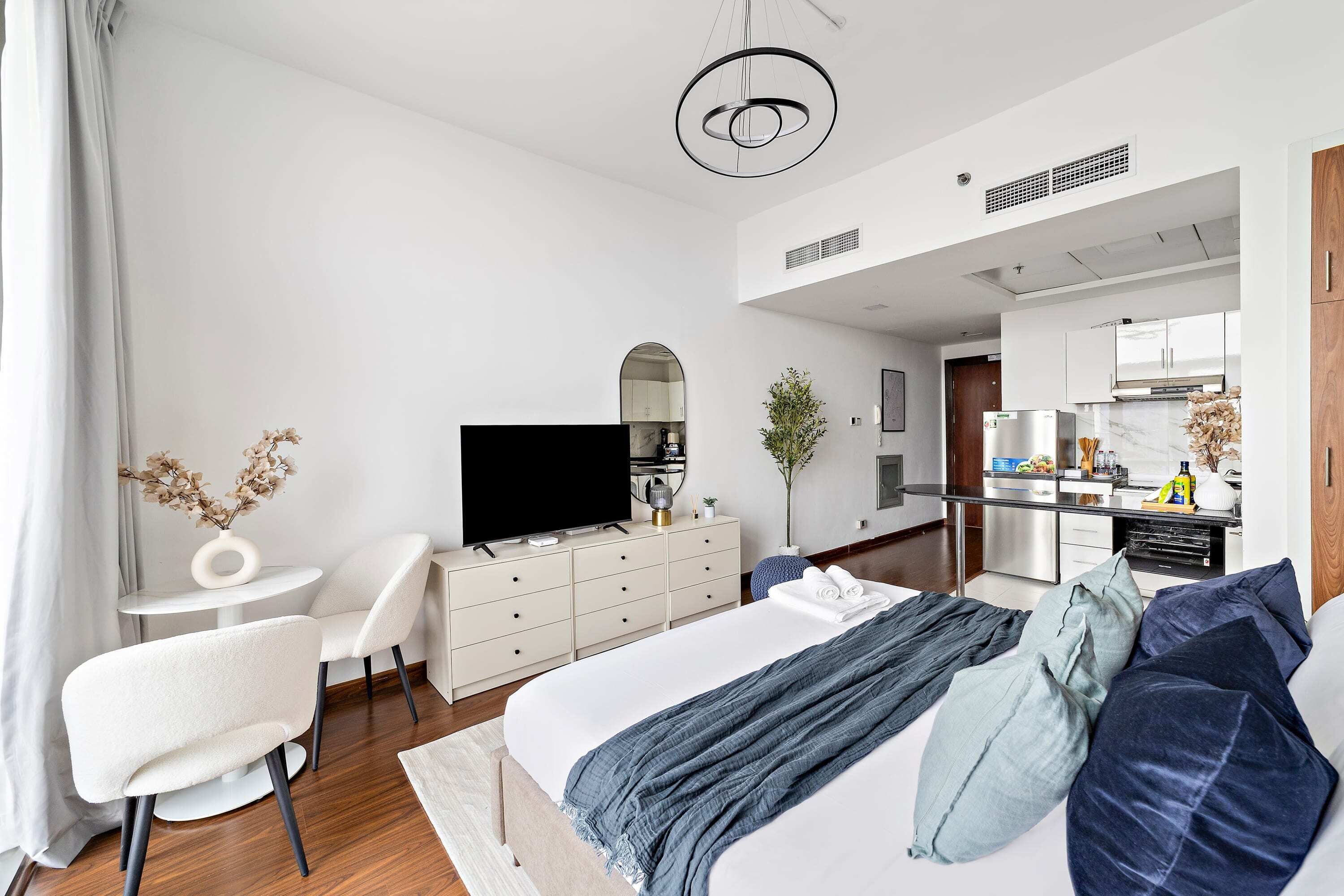 Une chambre d’hôtel moderne équipée d’un lit, d’une télévision, d’un coin repas et d’une cuisine.