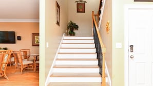 A staircase with white steps and a wooden handrail, leading to a white door.