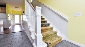 Un escalier avec des balustrades blanches et des marches recouvertes de moquette, menant à une porte.
