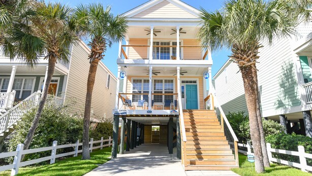 A two-story beachfront house with a covered front porch, a staircase leading to the entrance, and a white picket fence. - 2nd Row 4 BR Beach House with a Private Pool! Peachy Pleasure   (Surfside Beach)