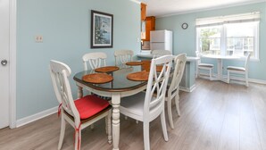 A dining area with a round table, white chairs, and a refrigerator in the background. - Oceanfront 5 BR Beach House! Sam's Shack (Surfside Beach)