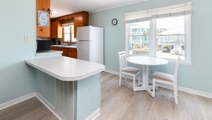 A kitchen with a white refrigerator, wooden cabinets, a white countertop, and a window with blinds. - Oceanfront 5 BR Beach House! Sam's Shack (Surfside Beach)