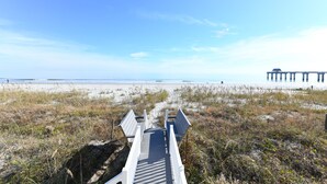 A wooden boardwalk leading to a beach with a pier in the background. - Oceanfront 5 BR Beach House! Sam's Shack (Surfside Beach)