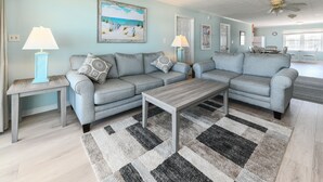 A living room with a sectional sofa, two side tables with lamps, a coffee table, and a patterned rug. - Oceanfront 5 BR Beach House! Sam's Shack (Surfside Beach)