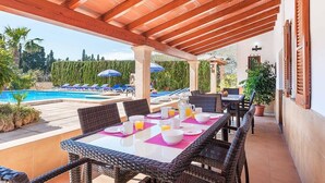 An outdoor dining area with wicker furniture, a pool, and umbrellas in the background. - Finca Vilar with pool, garden, 6 bedrooms, with A/C, 4 bathrooms, free Wifi (IB)
