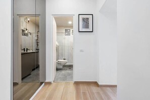 A modern bathroom with a toilet, shower, and a framed picture on the wall.