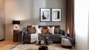 A modern living room with a sofa, a round coffee table, and two framed artworks on the wall. - Qult·co - Misty Night (București)