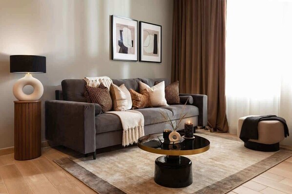 A modern living room with a sofa, a round coffee table, a lamp, and two framed pictures on the wall.