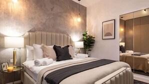 A modern hotel room with a large bed, bedside lamps, a mirror, and a potted plant. - Qult·co - Misty Night (București)