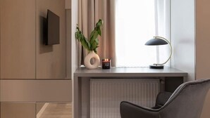 A modern room with a flat-screen TV, a desk with a lamp, a vase with a plant, and a radiator. - Qult·co - Misty Night (București)