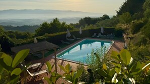 A pool with lounge chairs and a view of mountains.