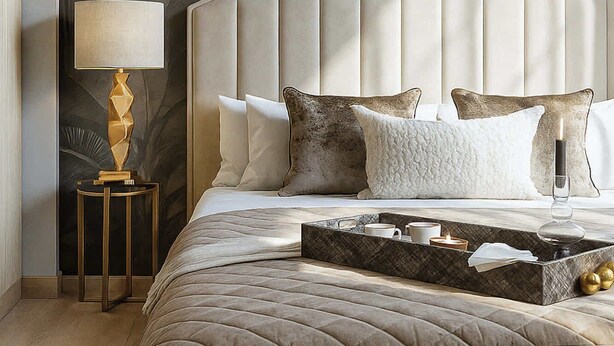 Un dormitorio con una cama grande, una mesita de noche, una lámpara y una pared con diseño de hojas.
