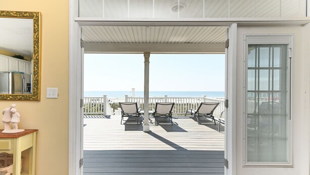 An open door leading to a deck with two chairs and a view of the beach. - Oceanfront 4 BR Beach House with a Private Pool! Surfin' Turf (Surfside Beach)