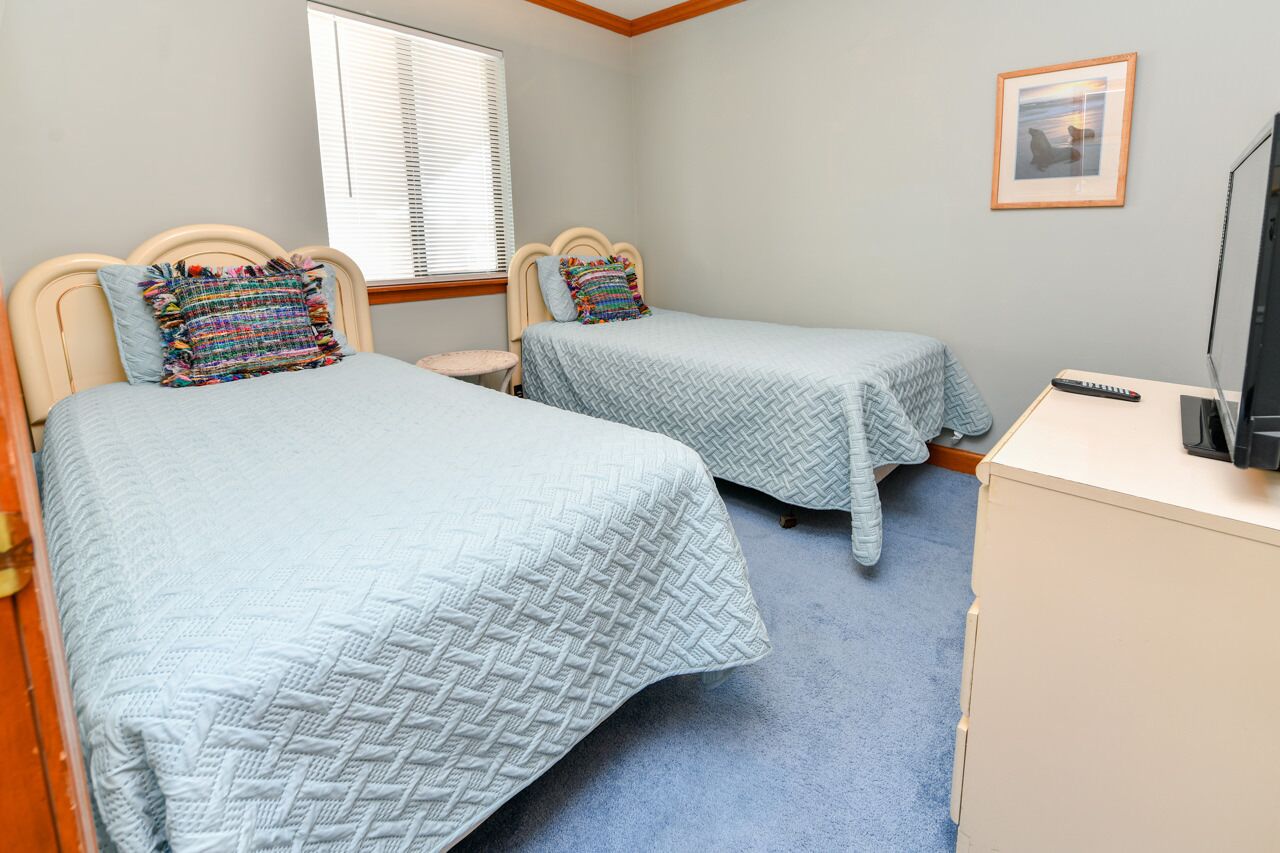 Une chambre avec deux lits, un bureau et une télévision.
