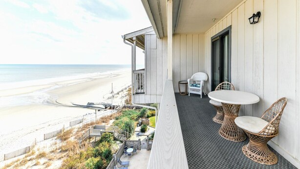 A balcony with wicker chairs and a table overlooking a beach. - Oceanfront 3 BR Condo with a Shared Pool! Surfwatch III 401  (Surfside Beach)