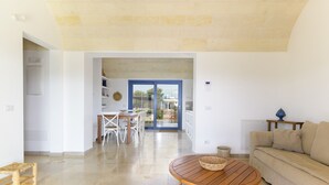 A spacious living area with a wooden coffee table, a beige sofa, and a dining area with white chairs. - Casa Blue con Piscina by Wonderful Italy (Ostuni)