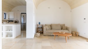 A spacious living area with a sofa, coffee table, and a kitchen in the background. - Casa Blue con Piscina by Wonderful Italy (Ostuni)