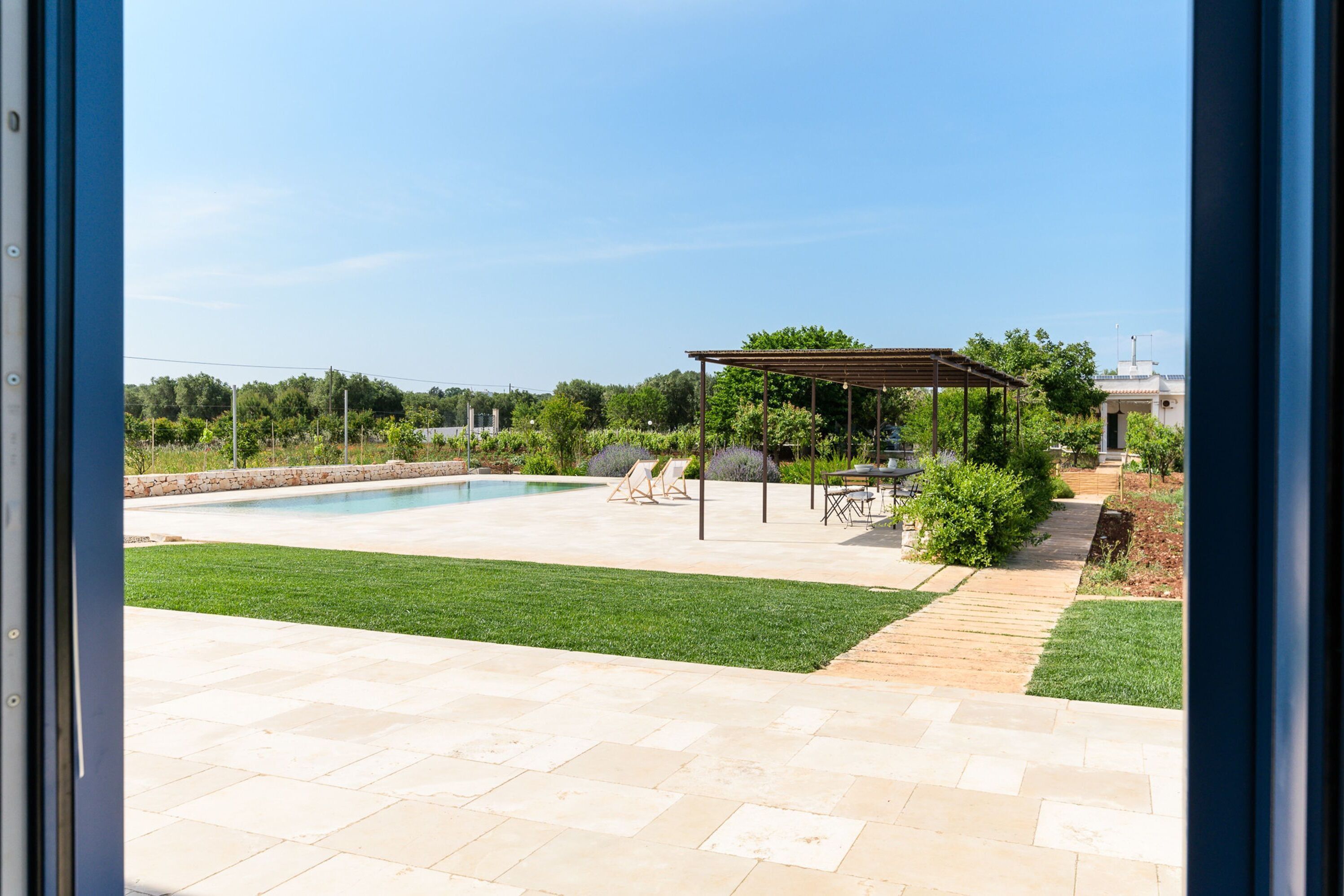A backyard with a swimming pool, a pergola, and a patio area.