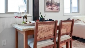 A dining area with a wooden table and chairs, a window with a view, and a cactus painting on the wall. - Cozy Hideaway Retreat Unit 4 near Durango, CO. (Durango)