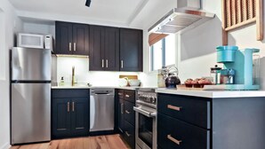 A modern kitchen with dark cabinets, stainless steel appliances, and a wooden floor. - Cozy Hideaway Retreat Unit 4 near Durango, CO. (Durango)