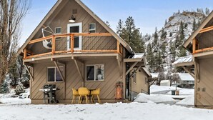 A two-story wooden cabin with a balcony, a grill outside, and a snowy mountain backdrop. - Cozy Hideaway Retreat Unit 4 near Durango, CO. (Durango)