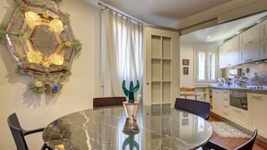 Un comedor con una mesa redonda de vidrio, sillas y un centro de mesa decorativo.