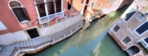 A narrow canal flanked by historic buildings with balconies and a small bridge. - MOORS private terrace San-Marco (Venice)