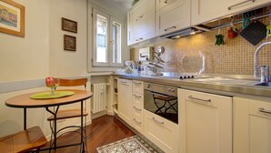 Una cocina con armarios blancos, una mesa de madera y un ventanal.