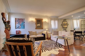 A living room with a sofa, chairs, a zebra rug, and a painting on the wall. - MOORS private terrace San-Marco (Venice)