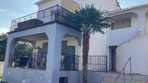 A two-story house with a balcony, a palm tree, and a staircase leading to the entrance. - Animaux Interdits Parking Privé Proche de la mer vue mer (Santa Lucia di moriani)