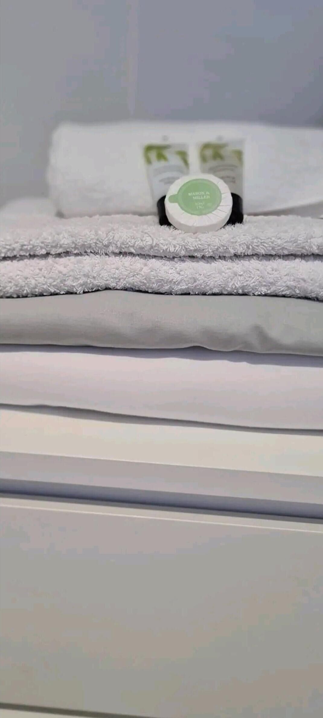 Une pile de serviettes blanches avec une étiquette verte posée sur une surface blanche.
