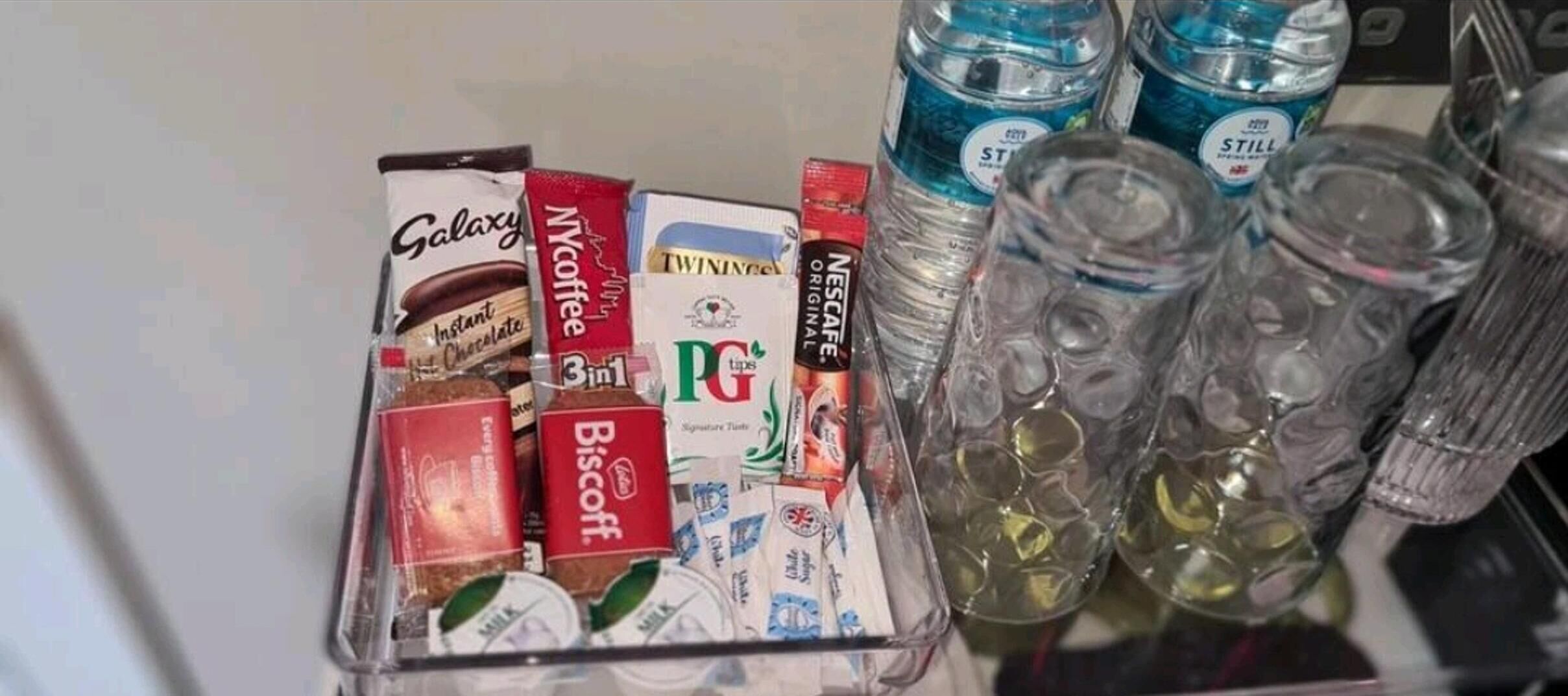 Un refrigerador lleno de diversos alimentos y bebidas, como café instantáneo, leche y agua embotellada.