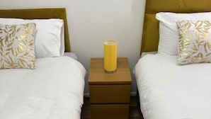 A hotel room with two beds, a nightstand with a lamp, and a patterned rug.