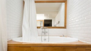 Une salle de bain avec un meuble-lavabo en bois, une baignoire blanche et un miroir avec un cadre en bois.
