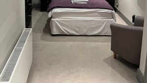 A modern bedroom with a bed, bedside tables, a TV, and a chair.