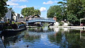 A canal with a blue bridge, boats, and buildings along the water.
